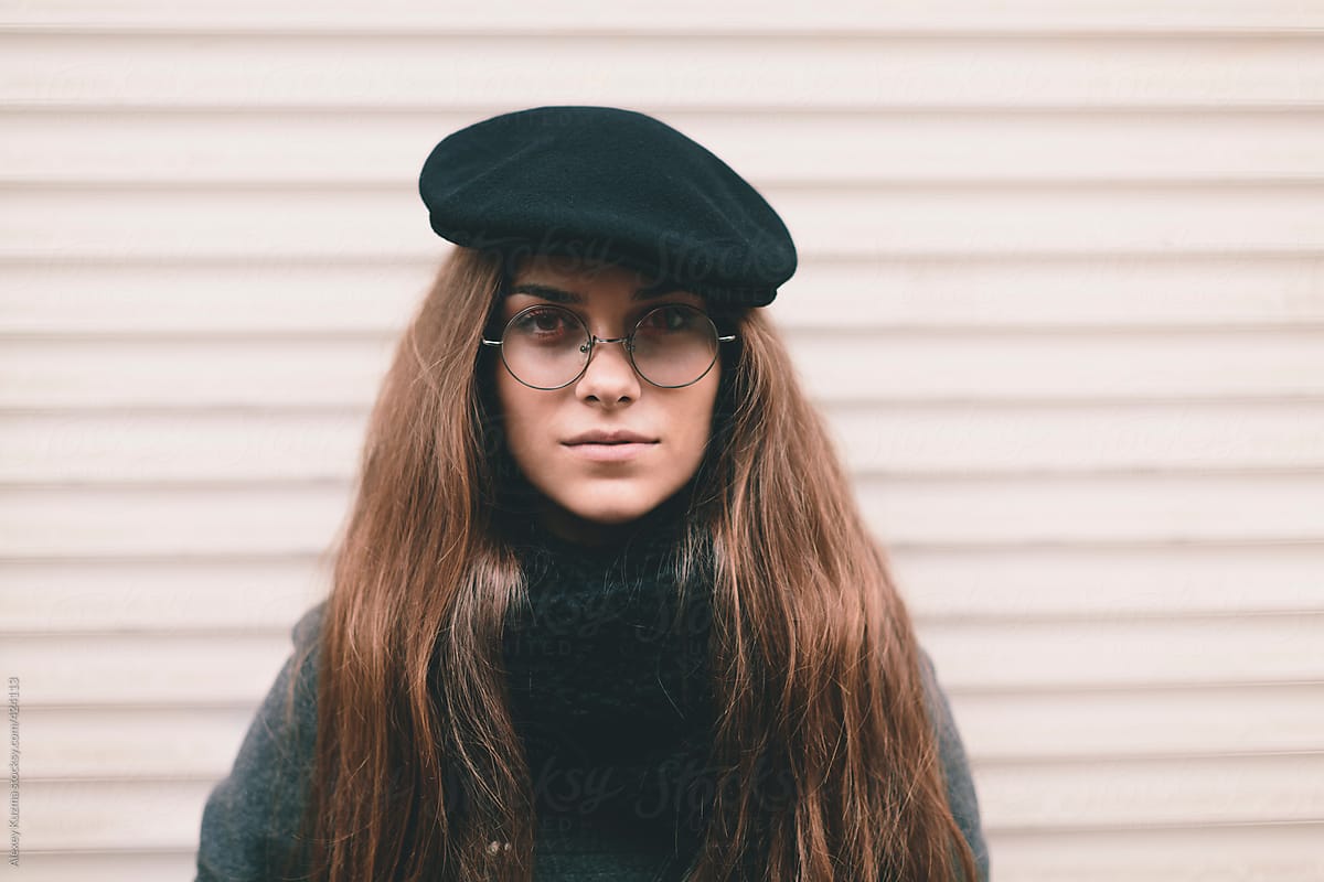 real young woman with black hat and round glasses .
