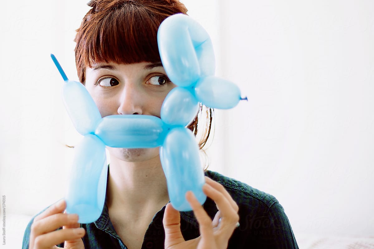 Young woman with dog balloon in front of her smiling mouth