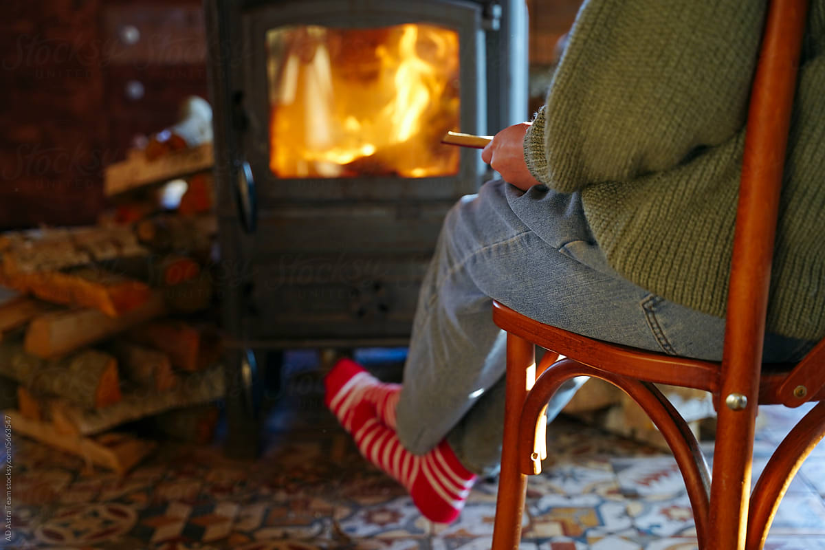 The legs of a woman in red socks are warming themselves