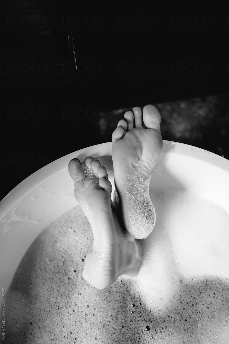 Anonymous  female feet in bathtub with bubble foam
