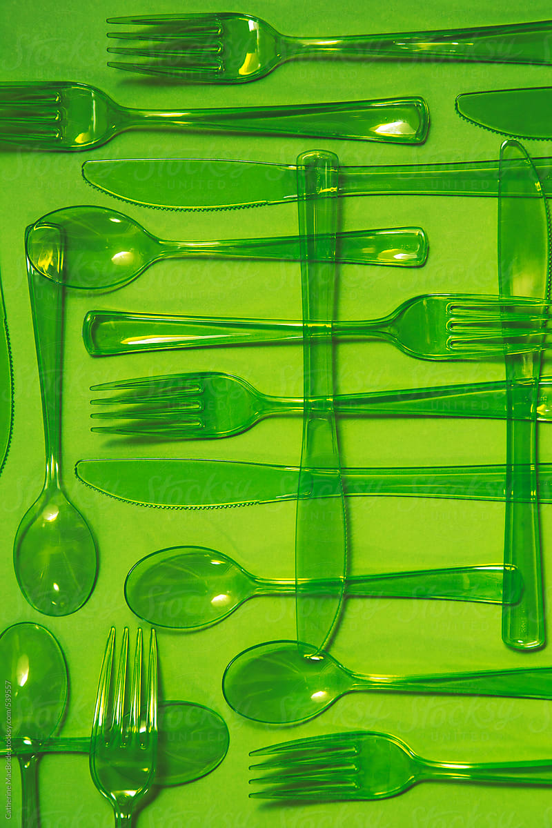 Green plastic cutlery on a green background...