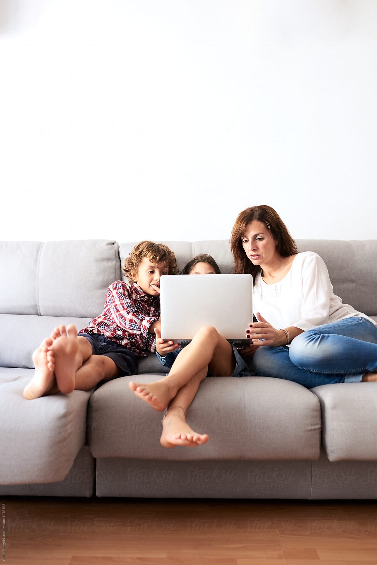 Barefoot Kids On Sofa Gaming» del colaborador de Stocksy «Guille Faingold»  - Stocksy