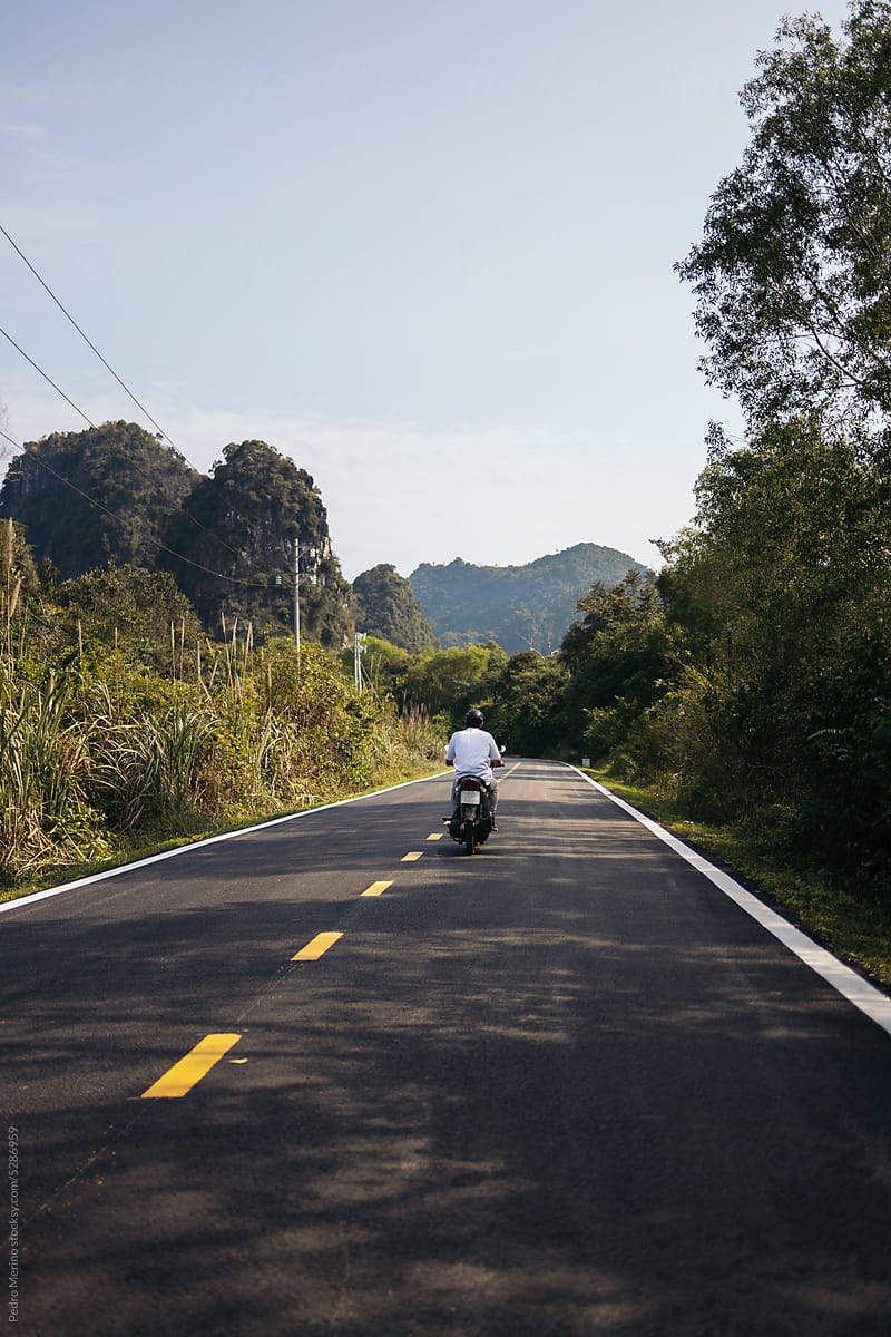 Man riding a motorbike through the jungle of Southeast Asia