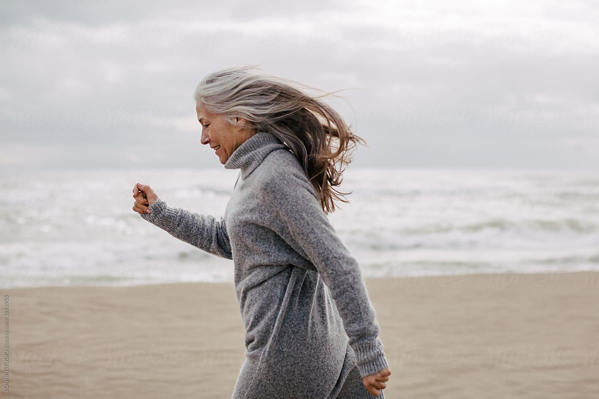 Active senior woman walking on the beach in winter.