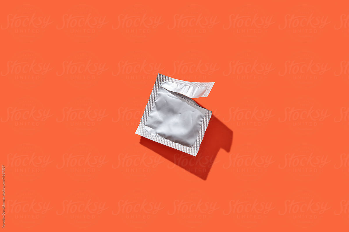 Empty silver condom package on plain background
