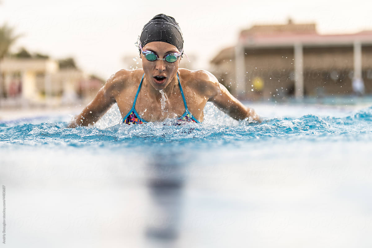 Girl is swimming in outdoor pool during her training