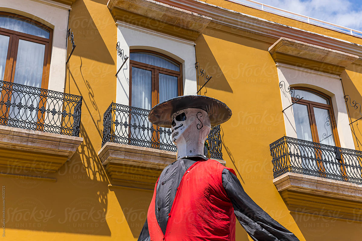 skull parading in front of a yellow building with balconies