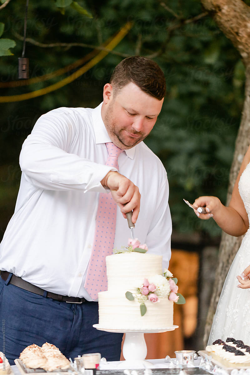 Groom Cutting Cake at Wedding