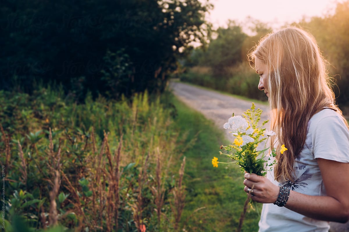 profile of A Woman Picking Wild Flowers By A Road Side At Sunset