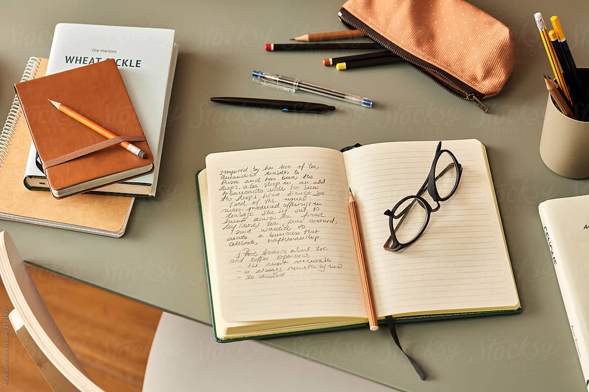 Notebook with handwritten text and glasses on desk