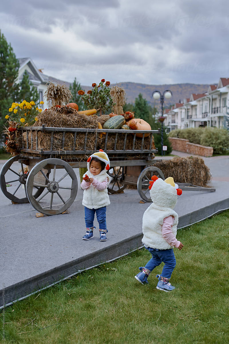 twin girl in a Halloween chicken costume walks down the street