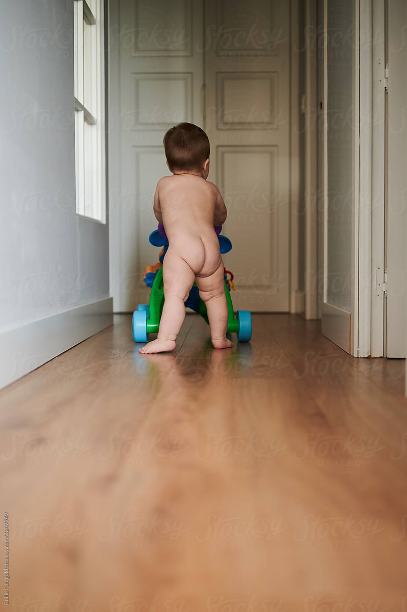 Unrecognizable nude baby playing in corridor