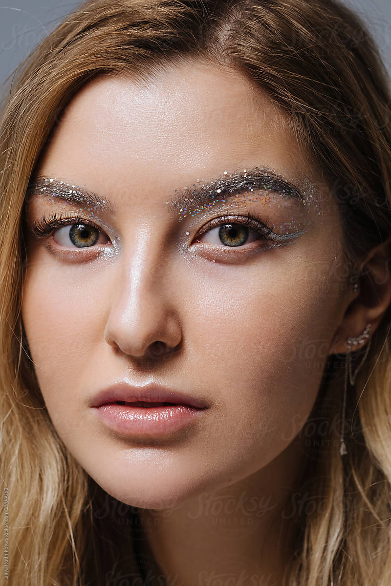 Crop face of model with silver glitter on brows