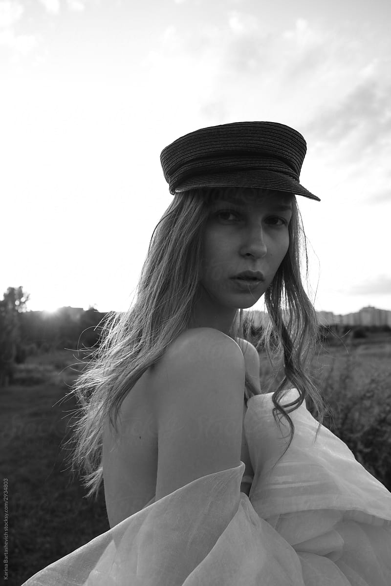 black and white portrait of a girl in a beret with long hair with bare shoulders and back on a walk