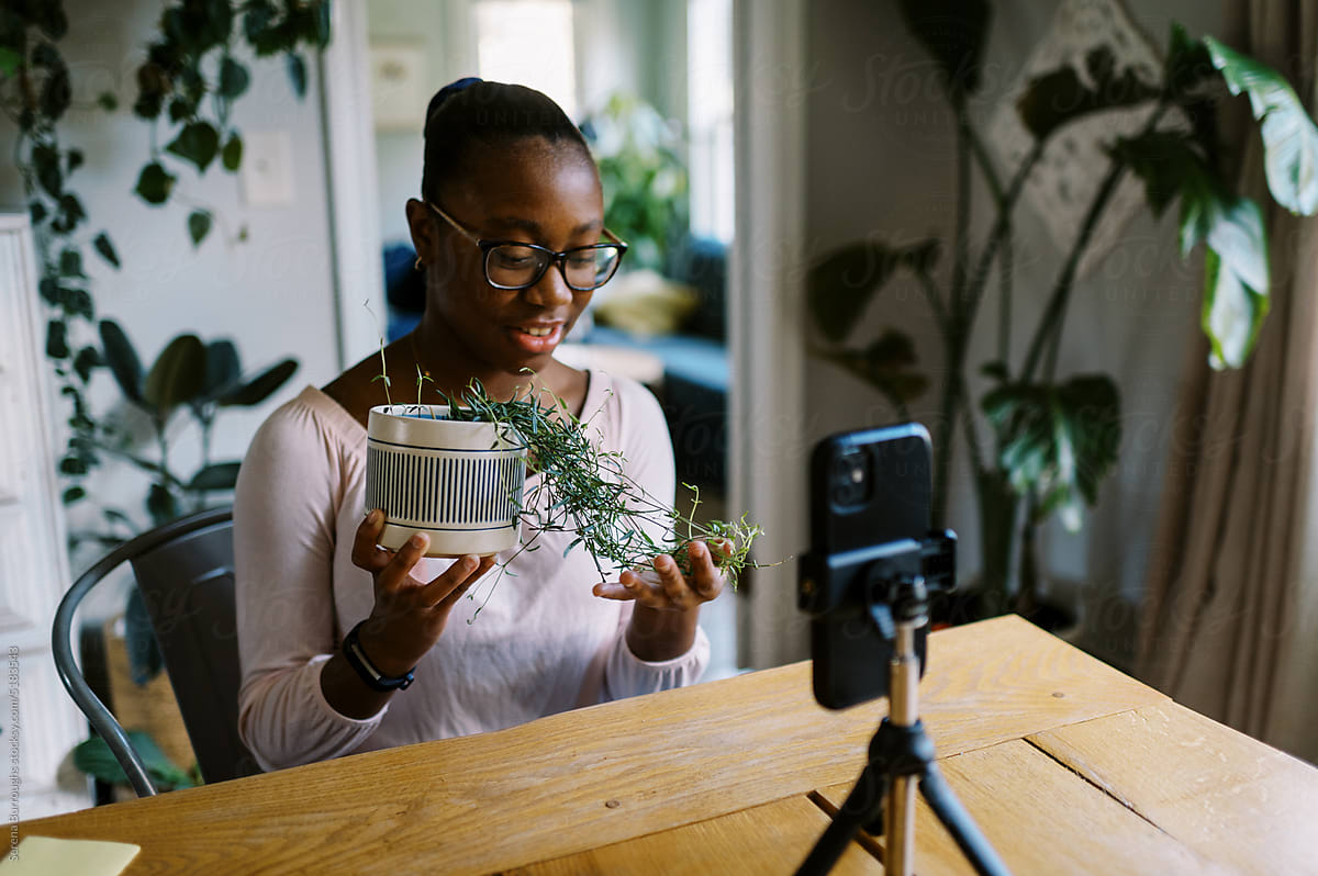 Smiling black girl vlogging about plants in her home