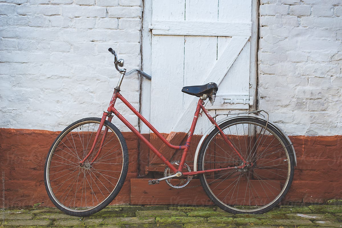 Very Old Red Bicycle Leaning to a Red and White Wall