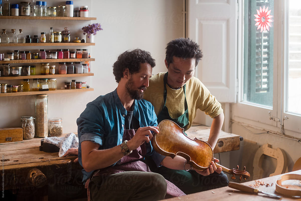 Two young luthiers discussing about an old violin