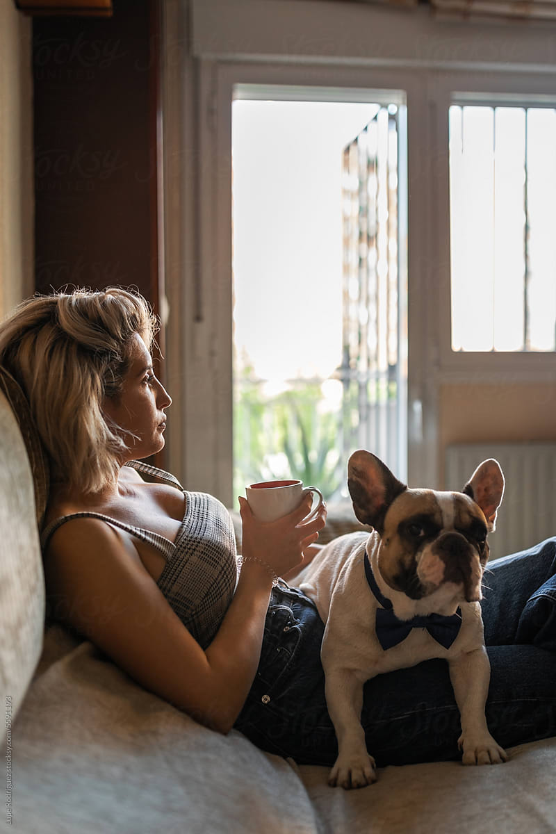 young woman drinking coffee with her dog at home