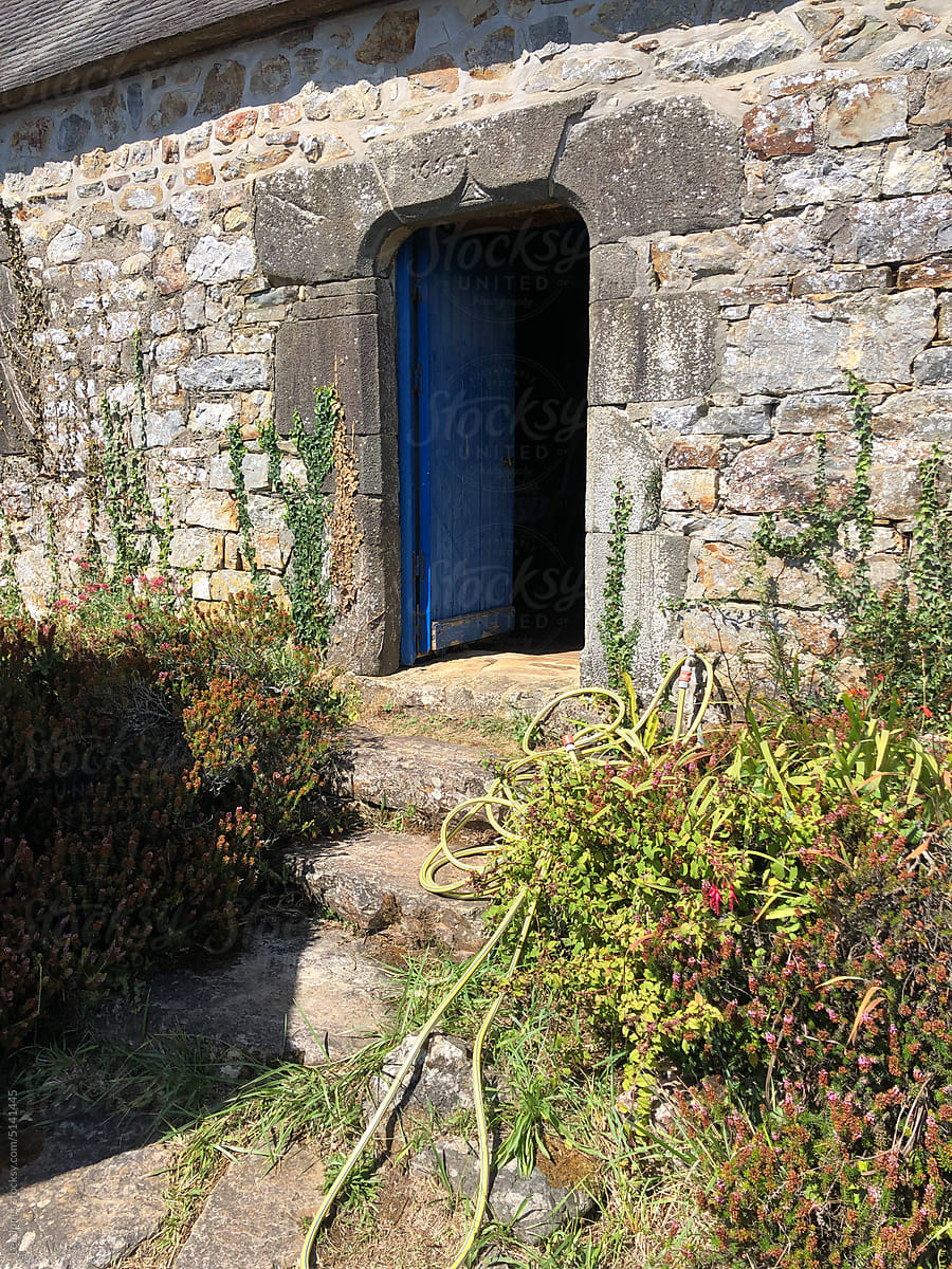 blue  door  on stone house in France, stone steps lead to the door.