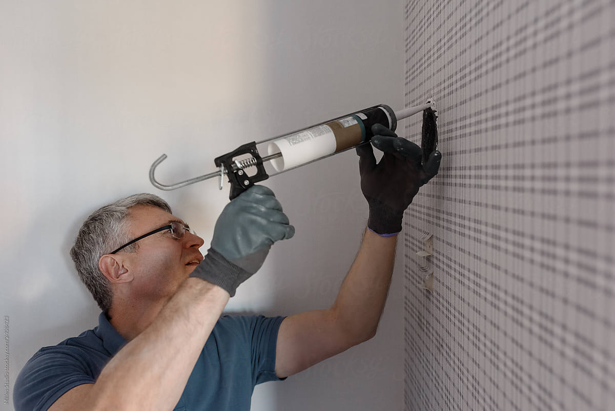 Man sealing ventilation hole in wall