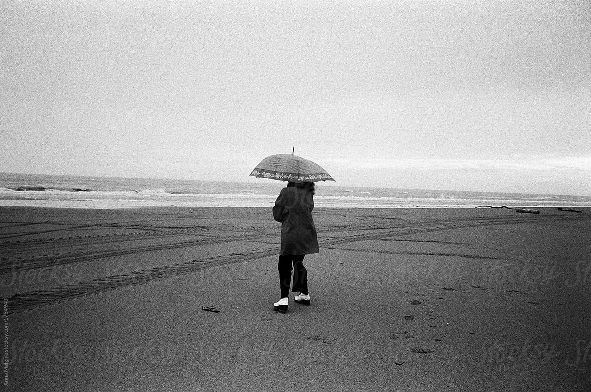 A woman walking with umbrella on a beach