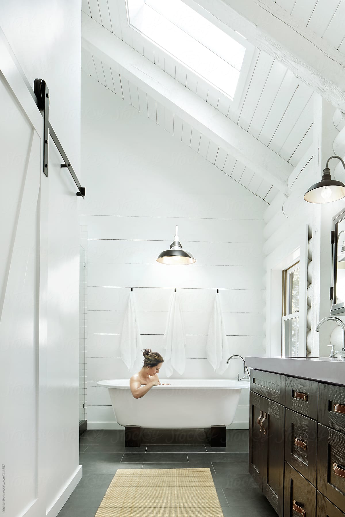 Woman relaxing in bathtub in bathroom of modern design farmhouse