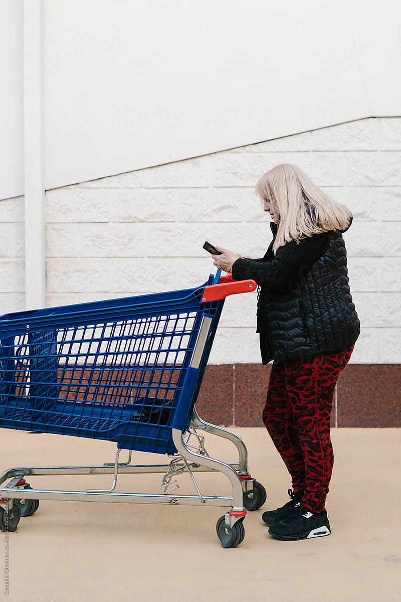Woman using smartphone standing with trolley