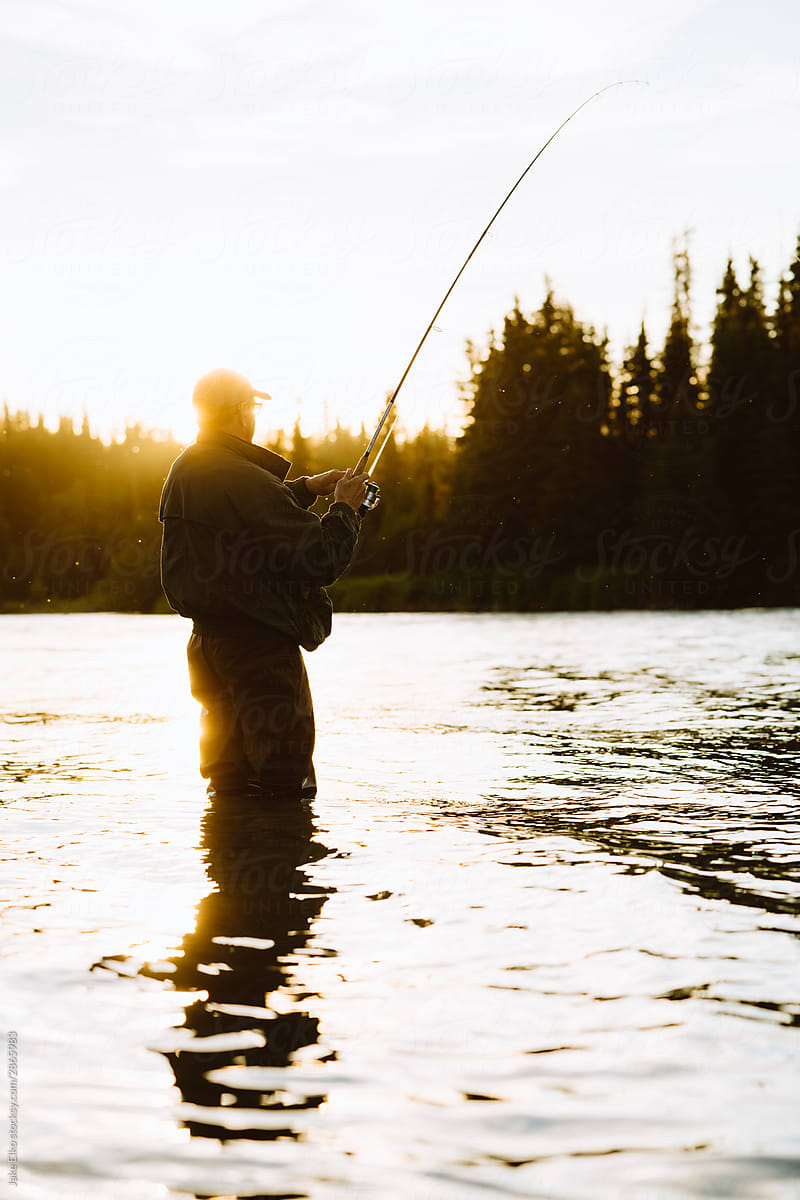Man Fishing for Salmon During Golden Hour in Alaska River