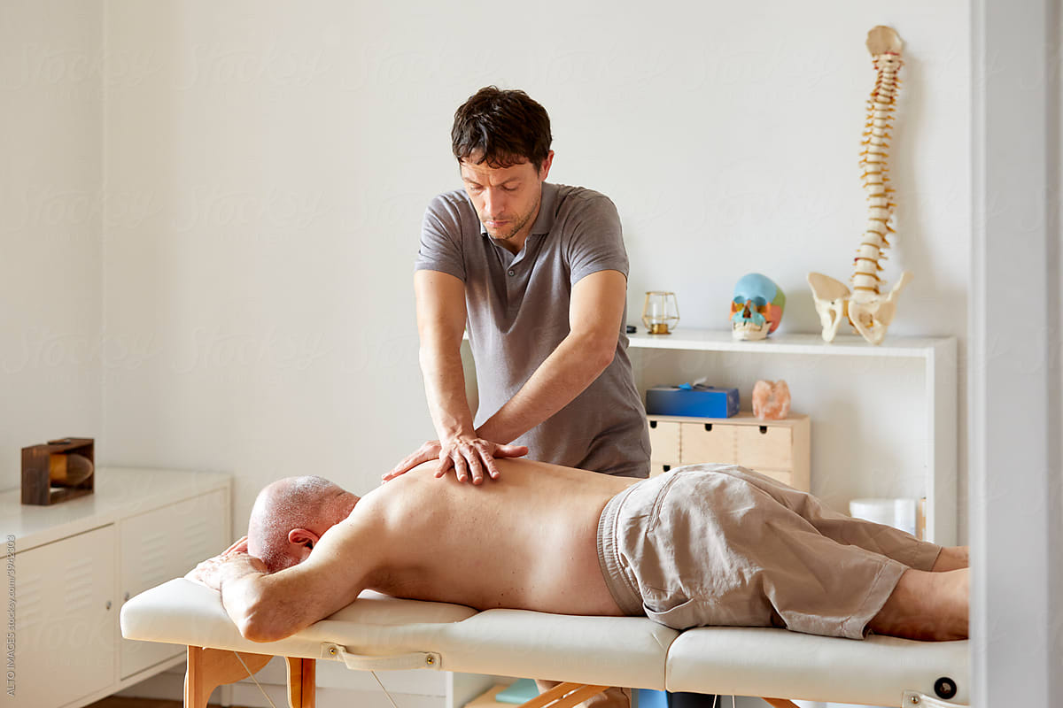 An osteopath massaging a senior patient