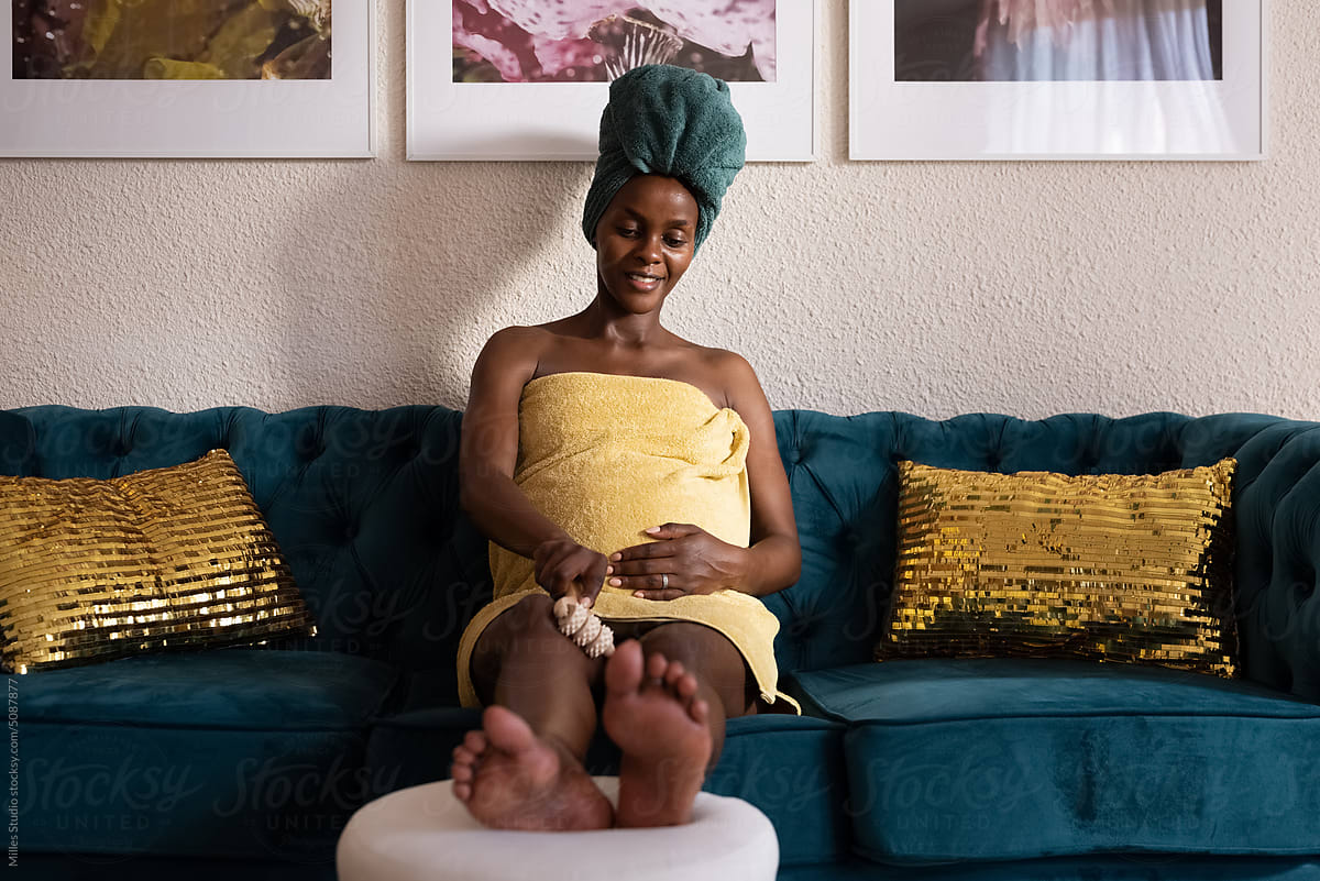 Peaceful black pregnant woman massaging leg