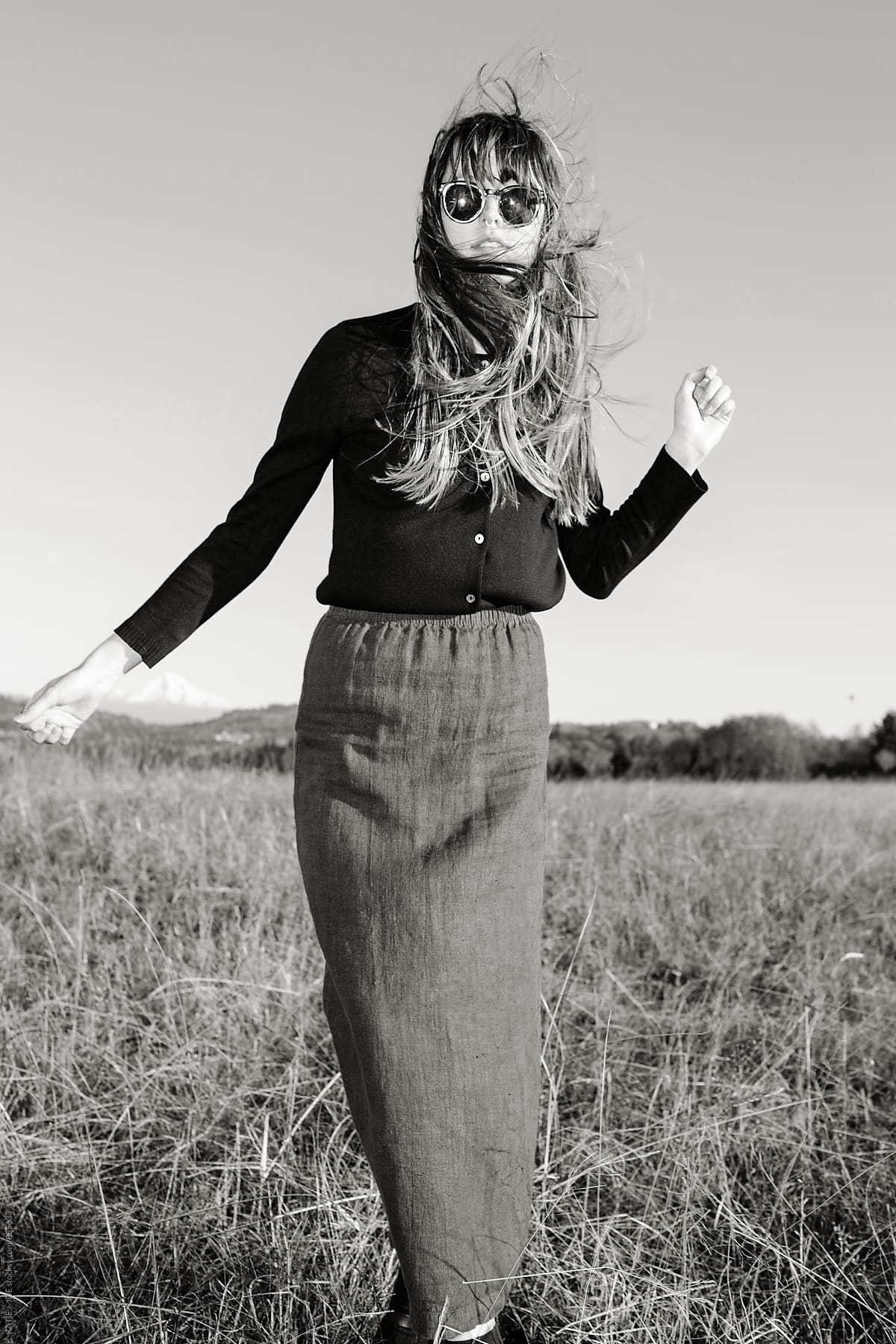 black and white photo of a girl with sunglasses and long hair blowing in the wind