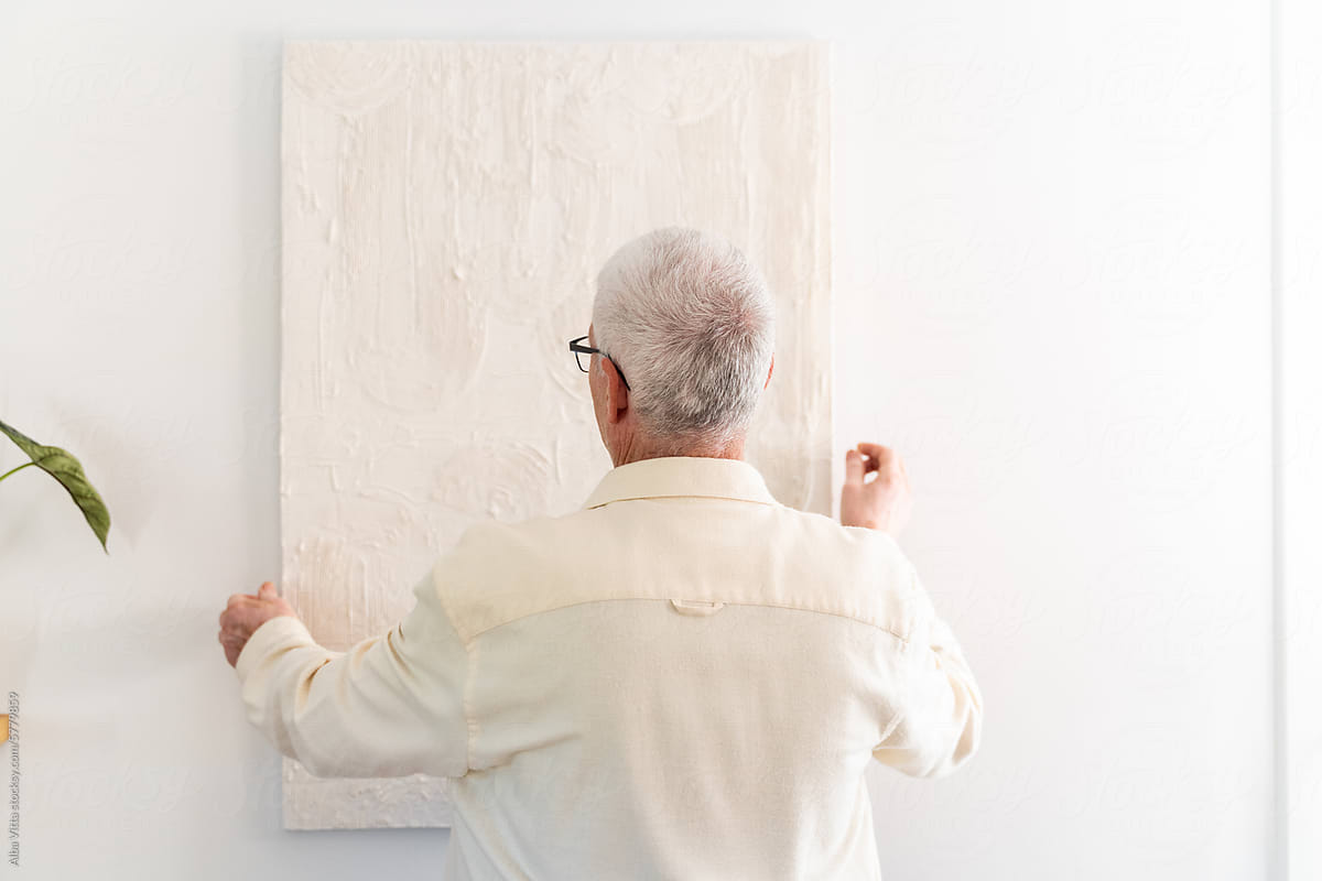 Man Hanging Painting On Wall