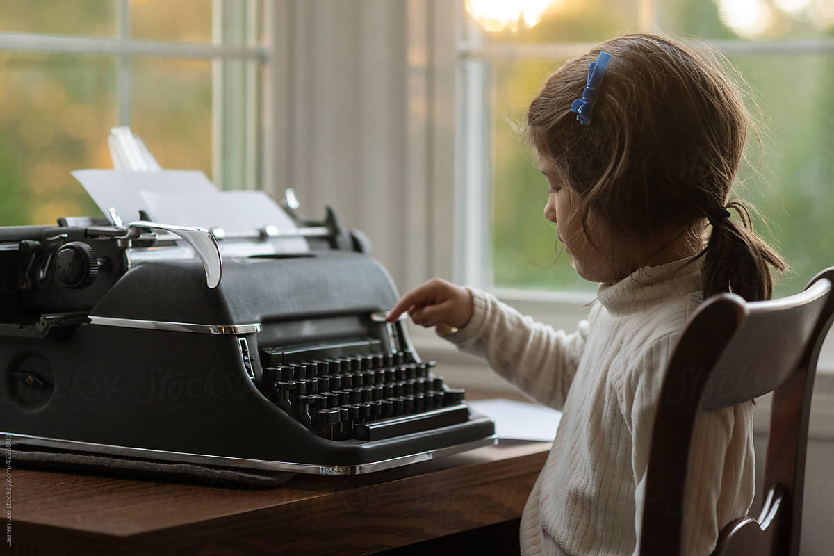 Little girl typing on typewriter