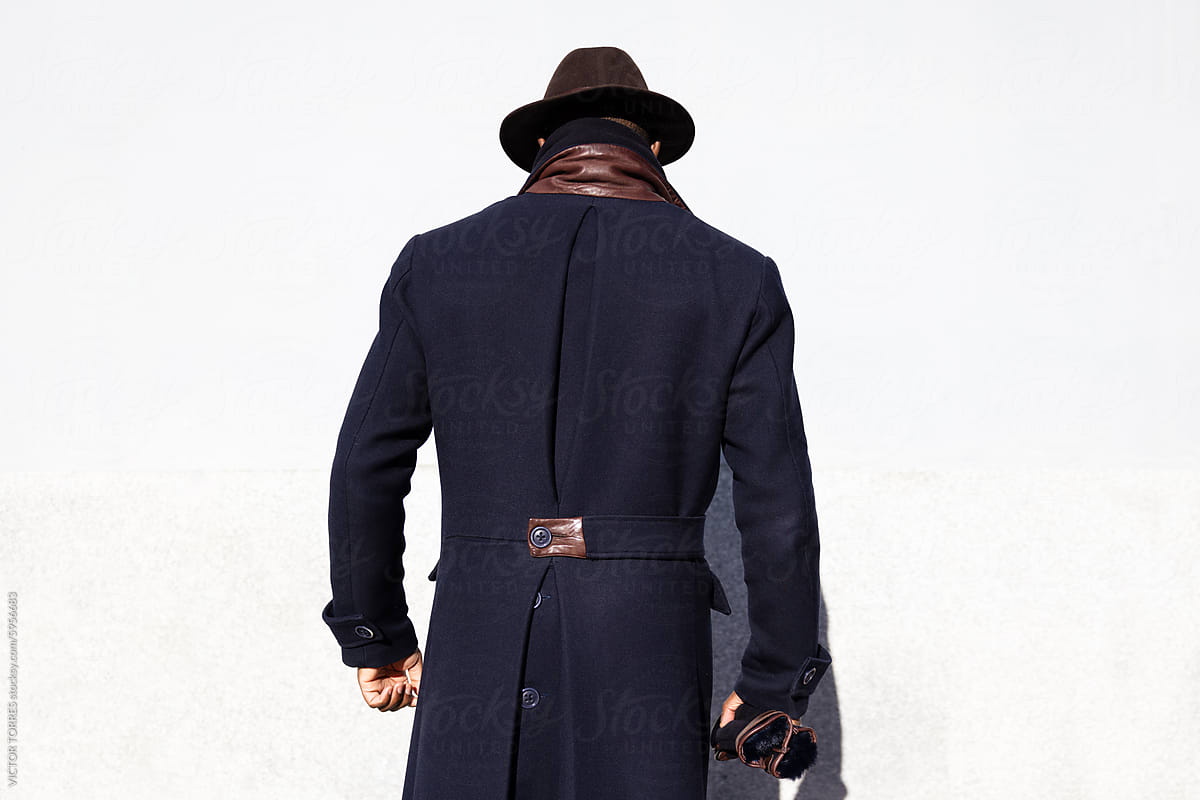 Man in elegant coat and hat from behind on white background