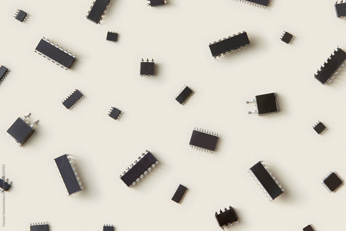 Integrated circuits scattered on beige background, close-up.