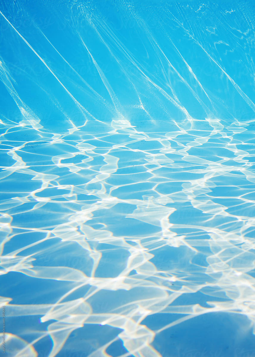 Underwater sight of sunrays drawing shadows on swimming pool bottom