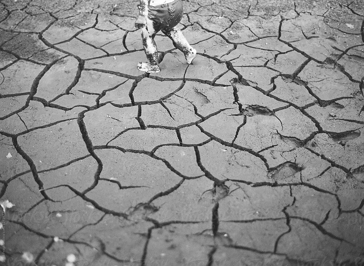 small child running through cracked mud