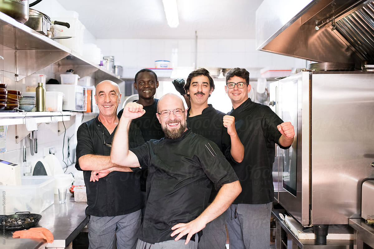 Lively chefs team posing at restaurant kitchen