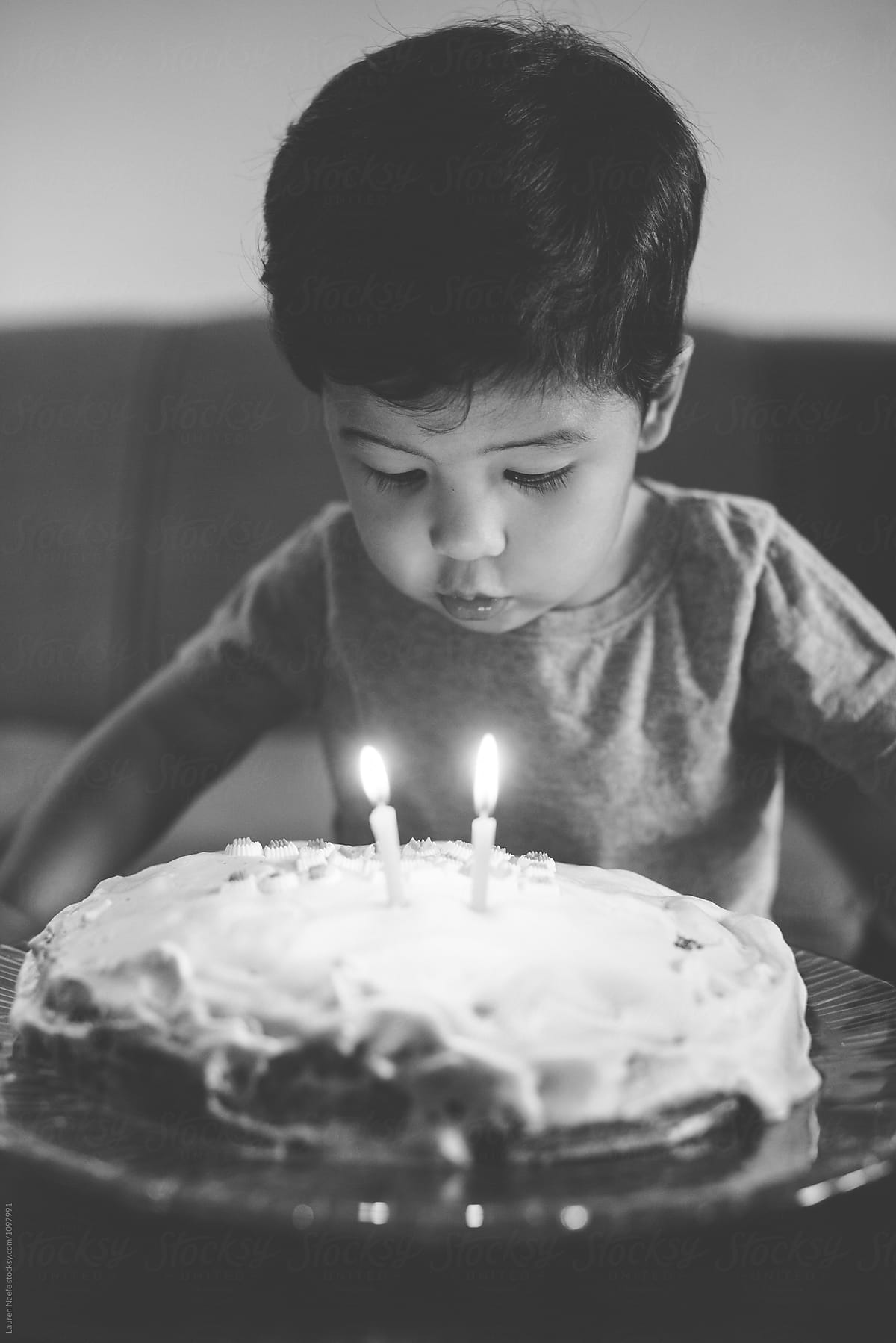 Little boy blowing candles on birthday cake