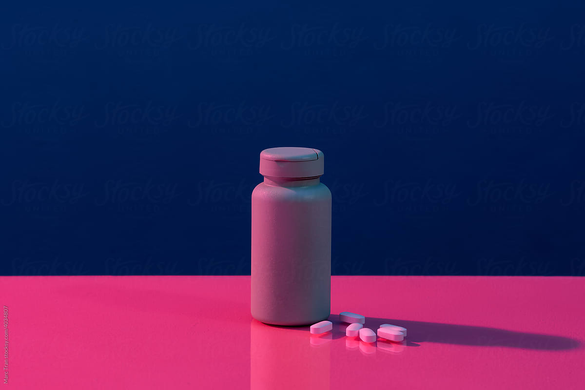 Creative layout with bottle, pills and capsules on vivid pink background