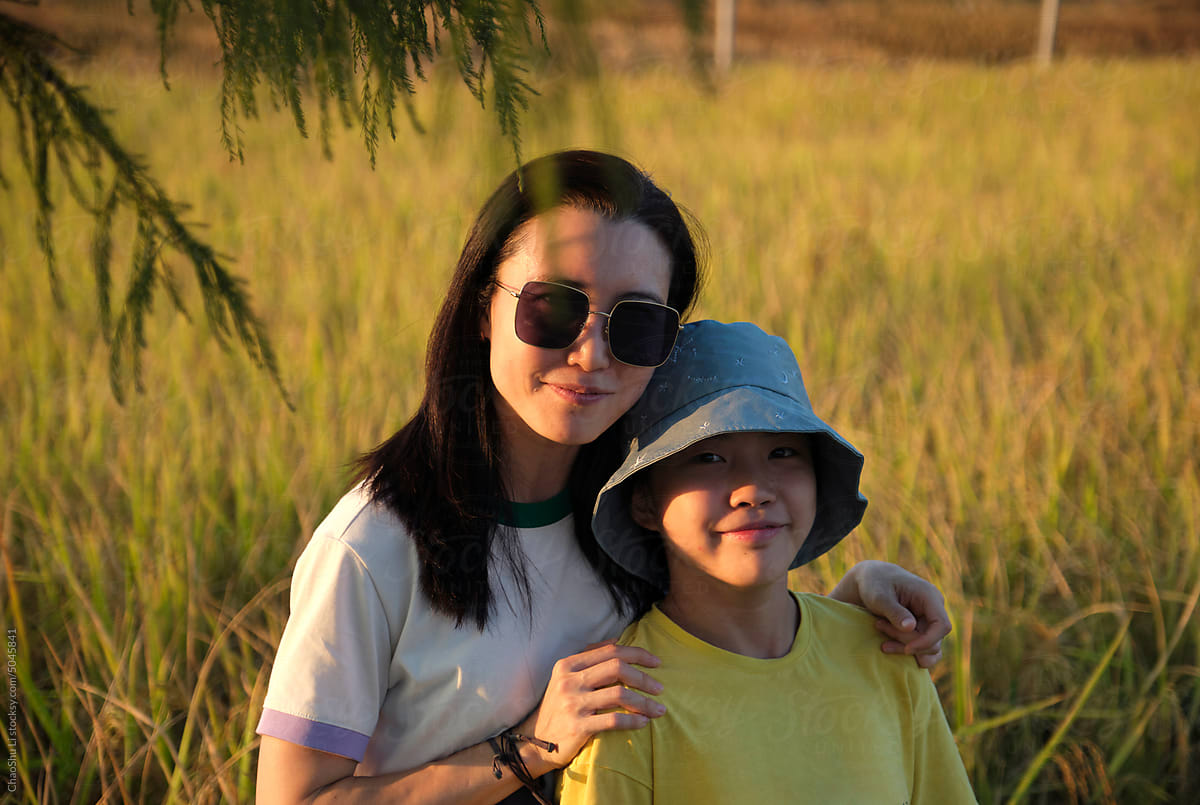 Asian mother and daughter, in the golden autumn harvest rice field