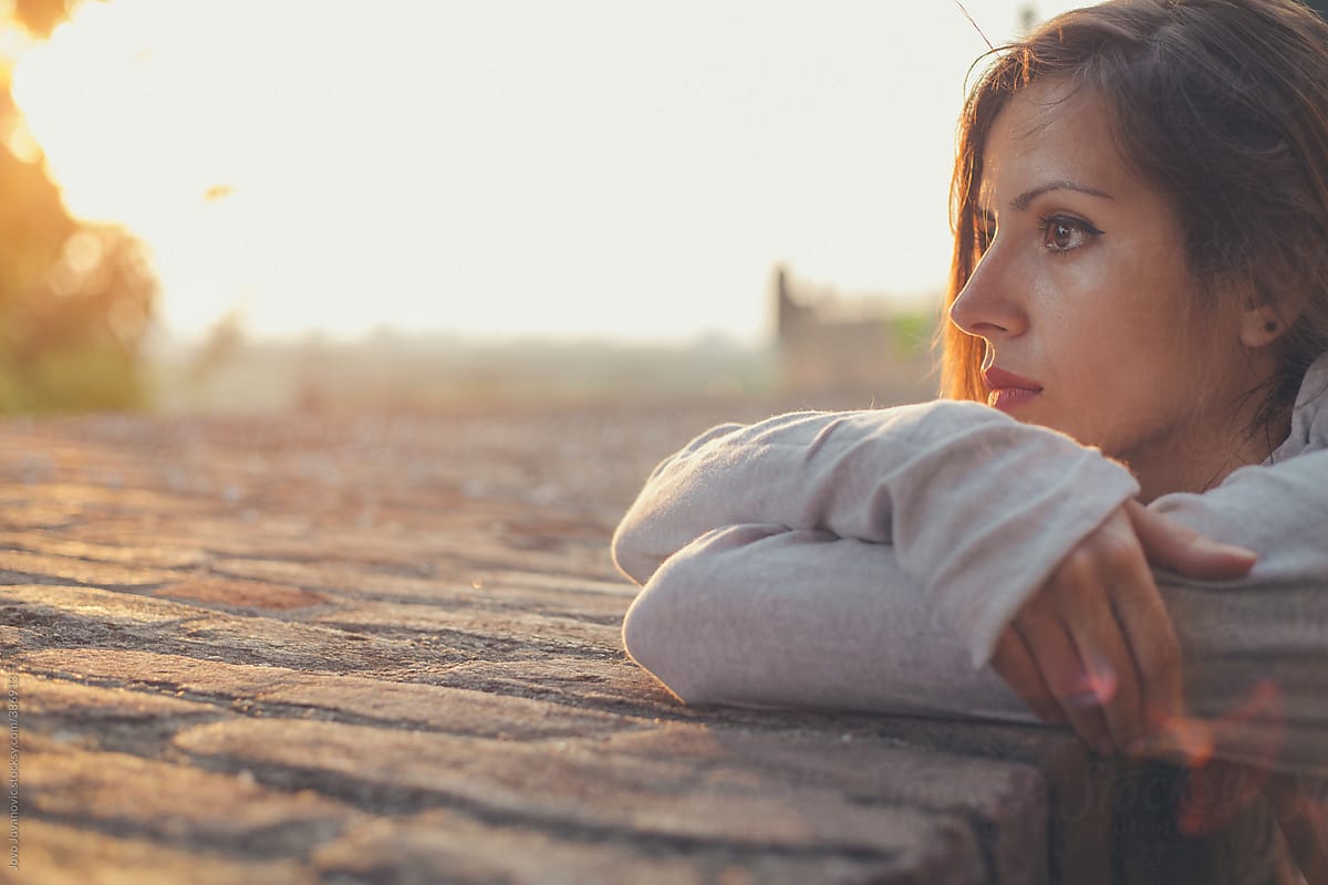 Young woman outdoors at sunset alone looking stressed
