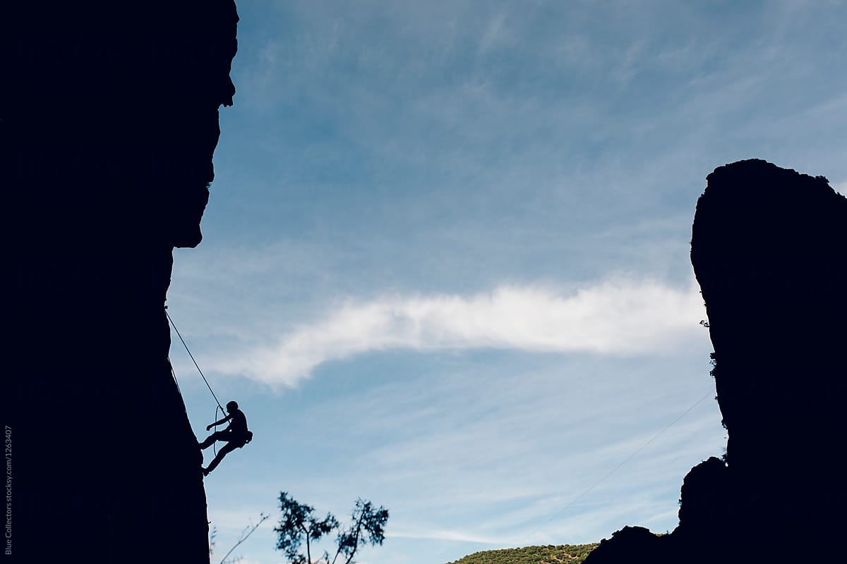 Alpinist silhouette climbing a rock wall