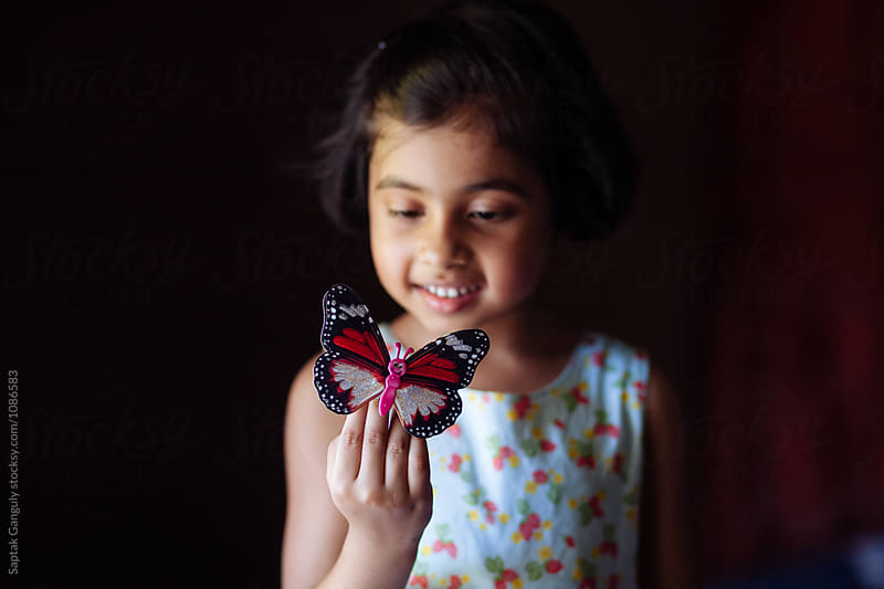 Little girl playing with decorative butterfly