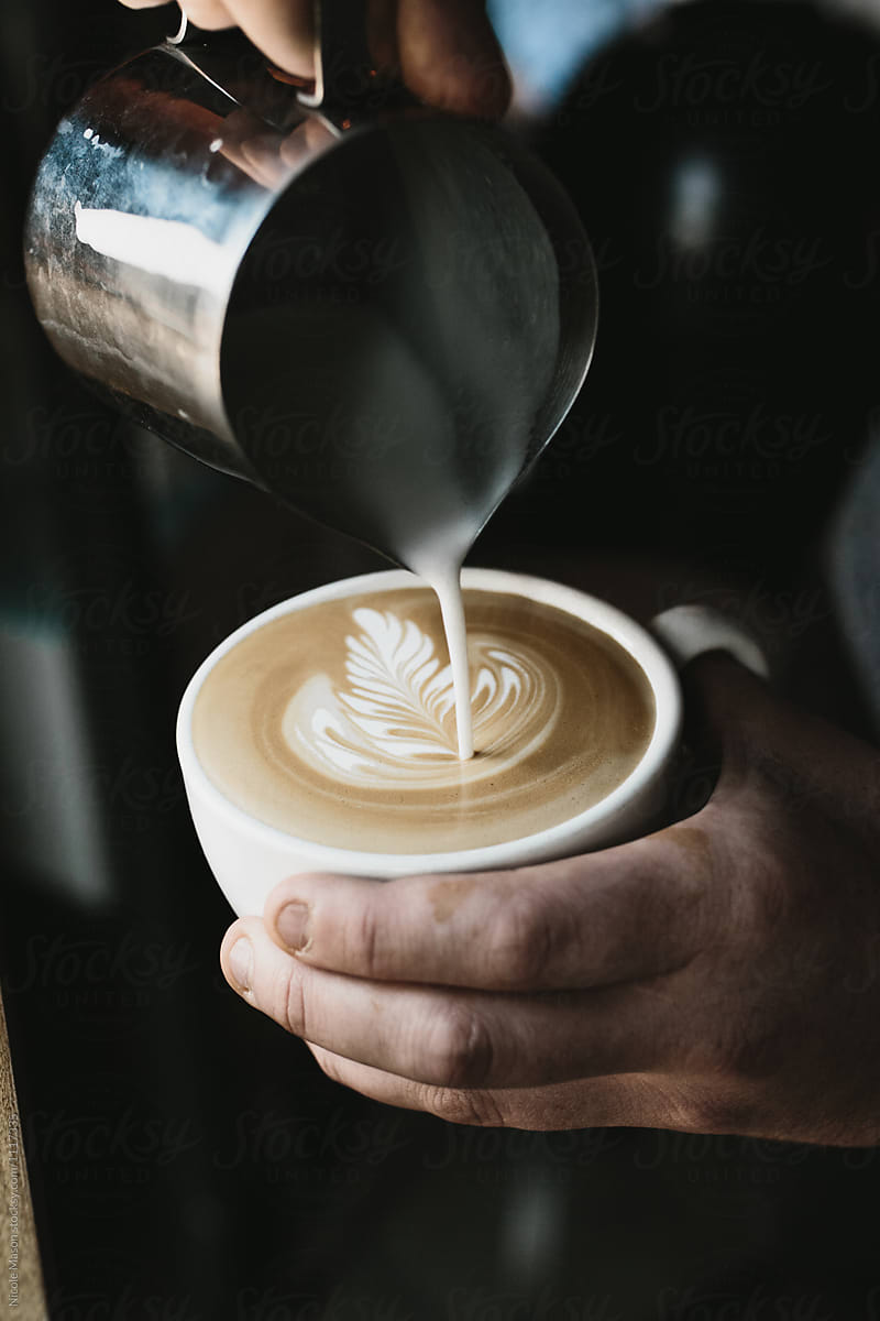 barista pouring milk to make latte art