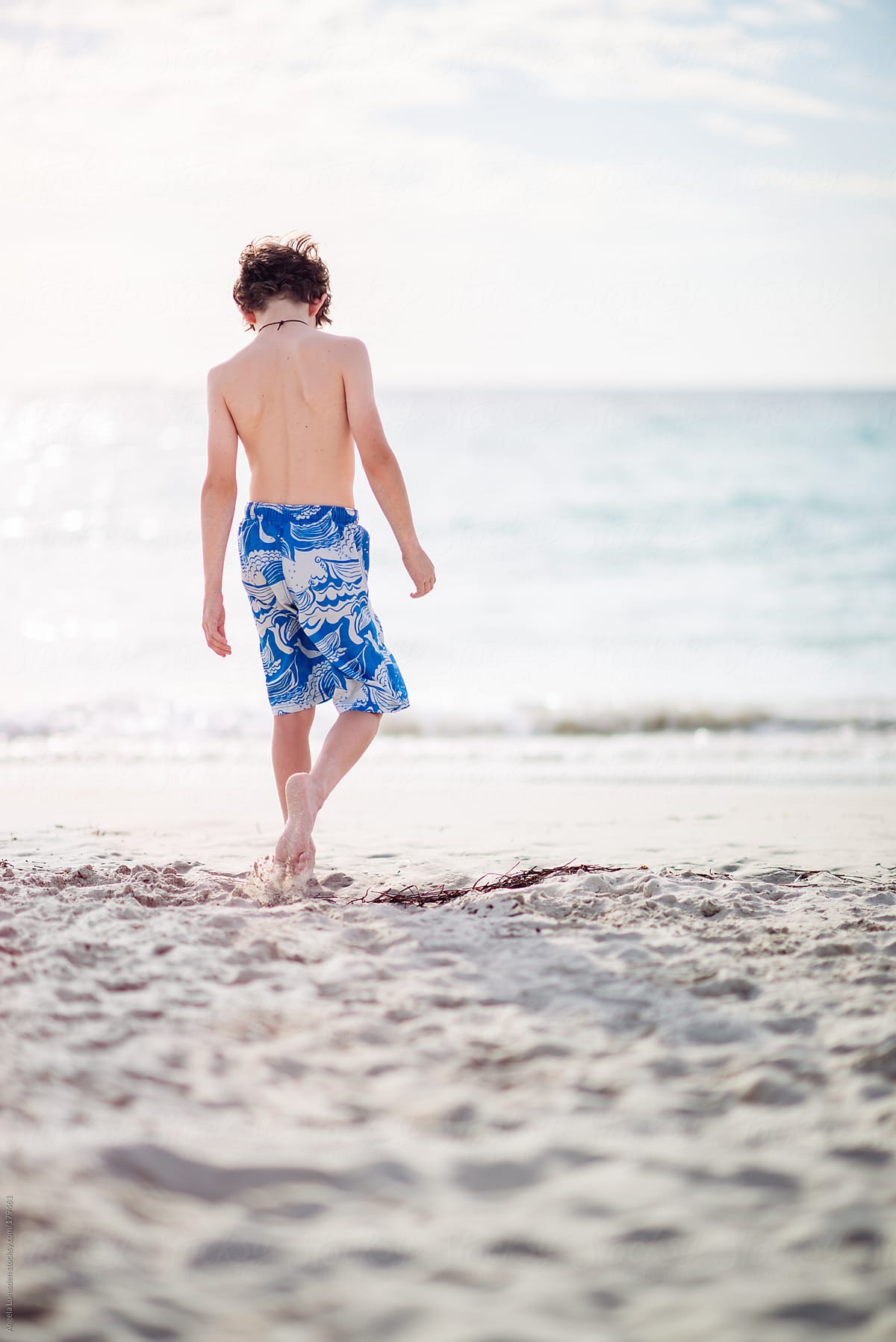 Boy in bathing suit walking towards the ocean
