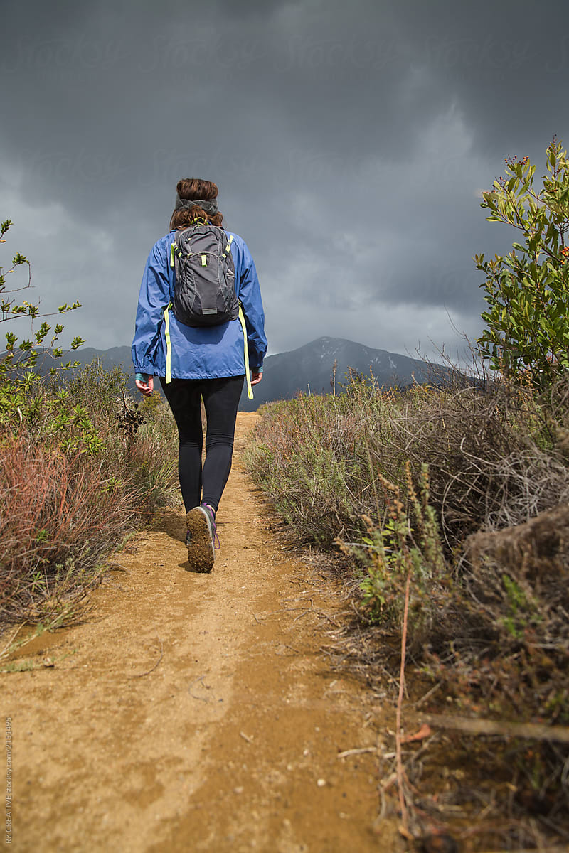 Woman hiking with dark storm clouds.
