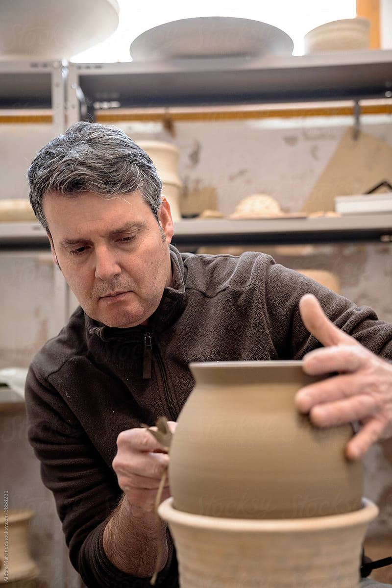 Man making marks on a ceramic jug in a workshop