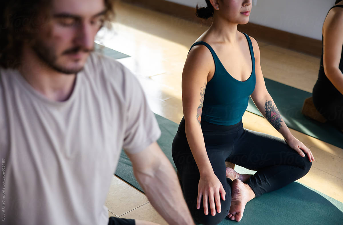 Meditative group yoga class practice inside modern studio.