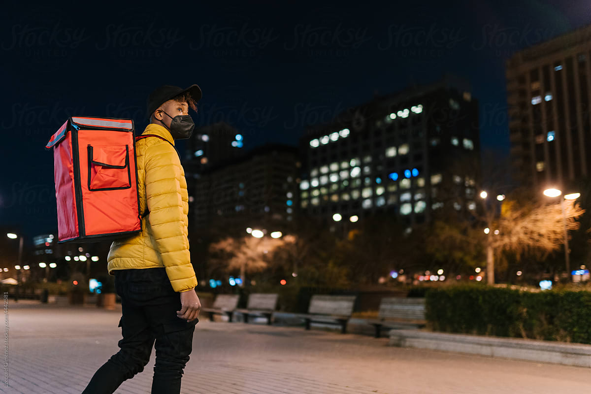 Delivery man strolling in modern city at night